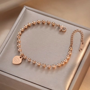 Rose gold stainless steel beaded bracelet with an engraved heart pendant for women