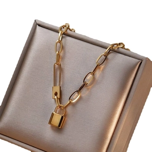 Polished gold titanium padlock pendant necklace on elegant champagne silk jewelry display