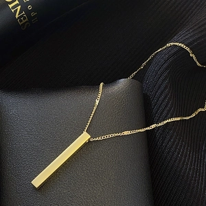 Macro detail of a polished gold vertical bar pendant on black leather texture