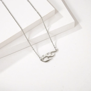 Collier avec pendentif flamme punk argenté sur un présentoir géométrique blanc épuré