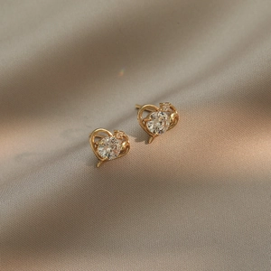Boucles d'oreilles cœur dorées avec pierres de zircon sur soie champagne élégante