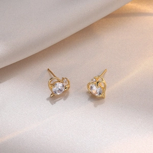 Boucles d'oreilles cœur dorées avec zircons étincelants sur un tissu en soie texturé