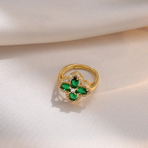 Anello regolabile in oro con trifoglio di zirconi verdi su sfondo di seta chiara