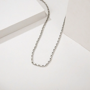 Minimalist silver box chain necklace made of polished stainless steel on white steps