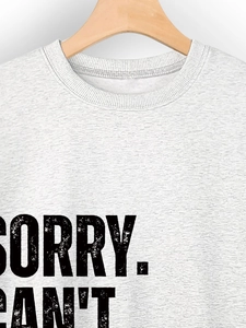 Detail of grey sweatshirt showing Sorry Can't vintage text print and fabric texture