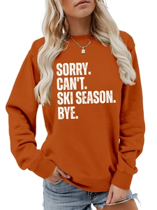 Detail of caramel orange sweatshirt featuring white SORRY CAN'T SKI SEASON slogan text