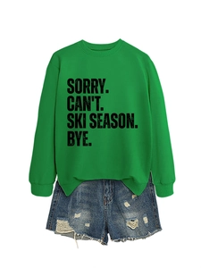 Flat lay of a green 'SORRY CAN'T SKI SEASON' sweatshirt with ripped denim shorts