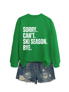 Flat lay of green 'Ski Season' sweatshirt paired with distressed denim shorts on white
