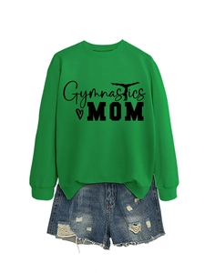 Flat lay of green Gymnastics Mom sweatshirt paired with distressed denim shorts