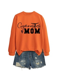 Flat lay of an orange Gymnastics Mom sweatshirt paired with ripped denim shorts