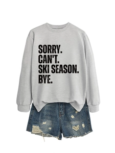Detailed view of grey sweatshirt with Sorry Can't Ski Season print and ripped denim shorts