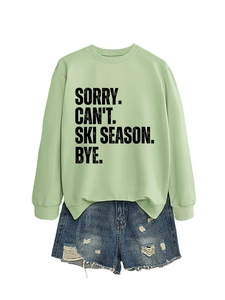 Flat lay of light green sweatshirt with Sorry Can't Ski Season print and denim shorts