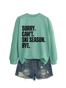 Close-up of mint green sweatshirt with black text print and distressed denim shorts