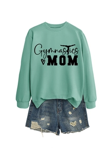 Flat lay of a mint green Gymnastics Mom sweatshirt paired with distressed denim shorts