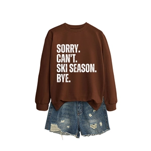 Brown Sorry Can't Ski Season sweatshirt with distressed denim shorts on white background