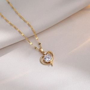 Elegant gold titanium heart necklace with cubic zirconia on textured warm background