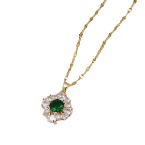 Collier trèfle plaqué or avec émeraude et chaîne à ondes d'eau sur fond blanc éclatant