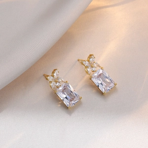 Elegant geometric gold earrings with rectangular zircon stones on champagne silk