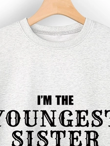 Close-up of I'M THE YOUNGEST SISTER black bold print on a grey crewneck sweatshirt