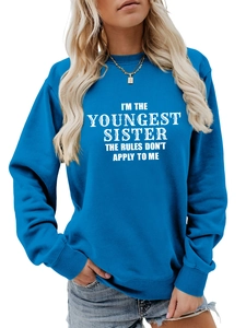 Detail of blue crewneck sweatshirt featuring white I'm The Youngest Sister slogan print