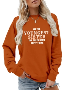 Close-up of youngest sister slogan print on burnt orange long sleeve crewneck sweatshirt