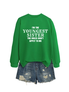 Flat lay of a bright green sweatshirt with 'youngest sister' slogan and frayed denim shorts