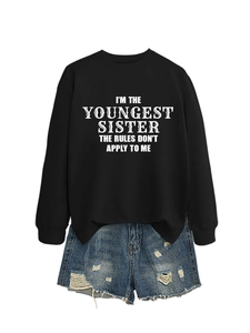 Flat lay of black sweatshirt with white slogan and distressed denim shorts on white backdrop
