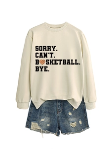 Flat lay of beige sweatshirt with basketball slogan and distressed denim shorts
