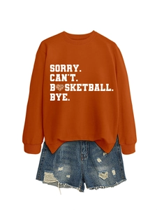 Close-up of orange sweatshirt with Sorry Can't Basketball Bye text and denim shorts