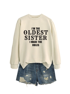 Flat lay of cream 'I'M THE OLDEST SISTER' sweatshirt paired with ripped denim shorts