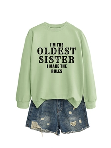 Detail of light green sweatshirt with I'm the oldest sister slogan and ripped denim shorts