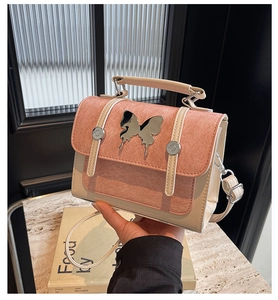 Detail of pink frosted shoulder bag featuring silver butterfly buckle and cream leather straps