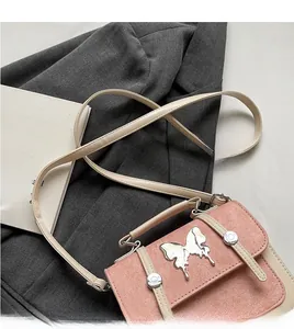 Detail of pink and cream crossbody bag featuring a silver metal butterfly buckle accent