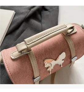 Detail of pink cylindrical handbag featuring a metallic butterfly and soft cream handles