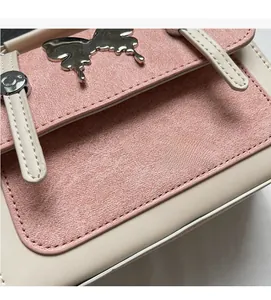Detail of pink textured fabric crossbody bag featuring a silver butterfly buckle