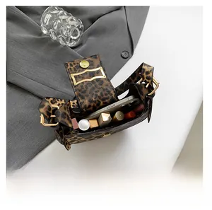 Leopard print crescent handbag showing internal capacity with phone and lipsticks