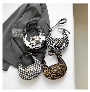 Detail view of four crescent shoulder bags in zebra, leopard, cow, and houndstooth patterns