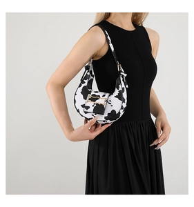 Detailed view of the cow print pattern and metal buckle on this half-moon hobo bag