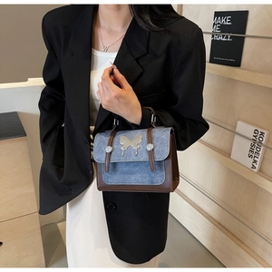 Detail of blue denim and brown leather handbag with silver butterfly buckle