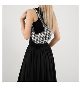 Detail of black and white houndstooth crescent bag with gold wavy buckle on shoulder