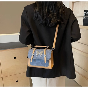 Vintage denim and leather patchwork crossbody bag featuring a silver metal butterfly