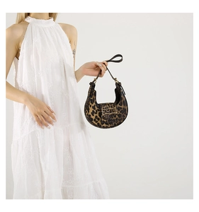 Detail of leopard print crescent bag with gold metal buckle on a white dress model