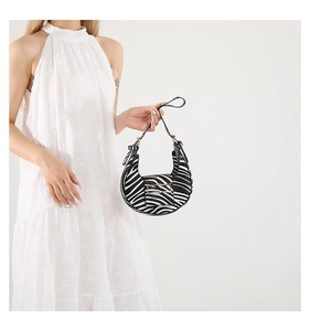 Detailed view of zebra print crescent handbag with a gold metal buckle on white floral dress