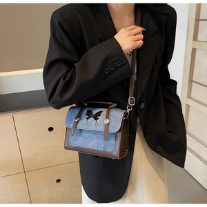 Close-up of contrast color bag with silver butterfly buckle and brown leather strap