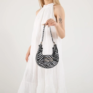 Chic zebra print half-moon underarm bag with gold buckle on white dress model