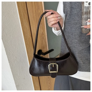Detail of dark brown glossy leather baguette bag with a golden horseshoe buckle