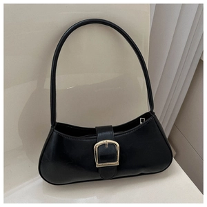 Detail of minimalist black underarm bag with large gold buckle on a stylish chair