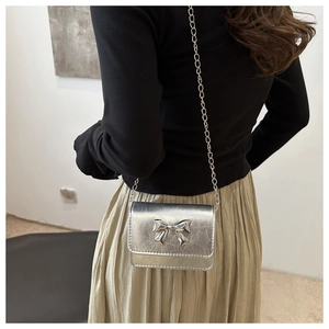 Silver metallic quilted mini bag with bow detail shown on model for size perspective