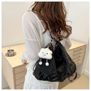 Close-up of large black wrinkled PU leather tote bag with a white plush cloud charm