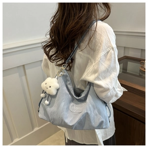 Détail du cabas en nylon bleu clair avec un joli pendentif en peluche nuage blanc